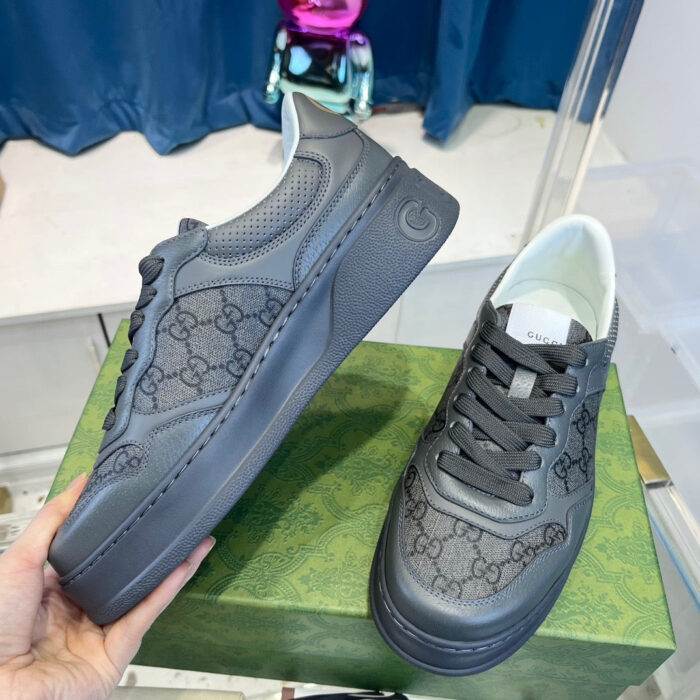 Sneakers di lusso in pelle nera, design elegante su scatola verde brillante.