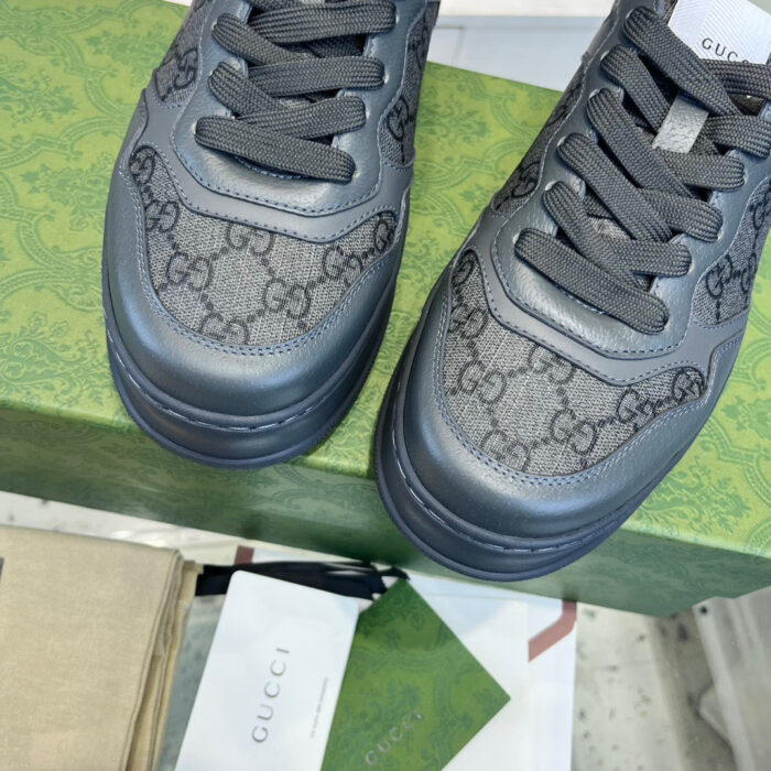 Sneakers Gucci nere su scatola verde elegante, dettagli monogramma di lusso e stile moderno.