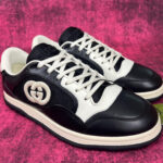 Sneakers di lusso nero e bianco con logo iconico e design moderno.
