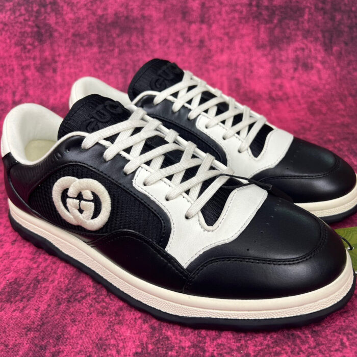 Sneakers di lusso nero e bianco con logo iconico e design moderno.