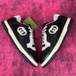 Sneaker di lusso nere con logo elegante su sfondo rosa vibrante e suola robusta