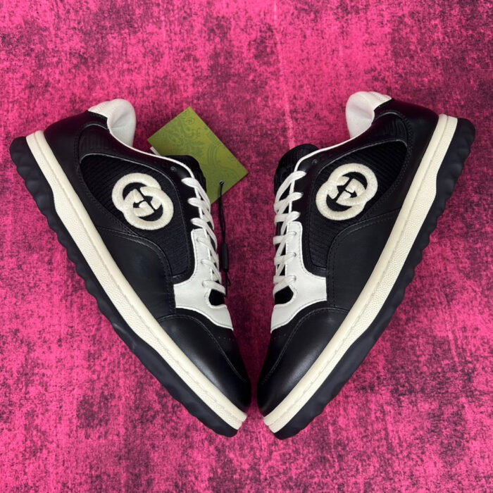 Sneaker di lusso nere con logo elegante su sfondo rosa vibrante e suola robusta