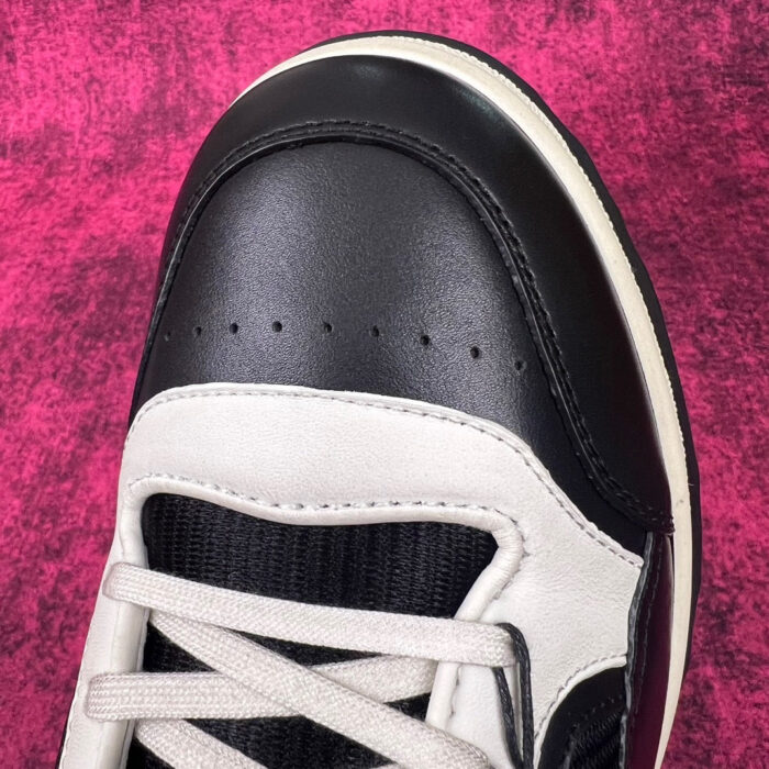 Sneaker elegante in nero e bianco con dettagli moderni e cuciture di alta qualità.