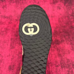 Sole di scarpe di lusso con logo interso in background magenta vivace.