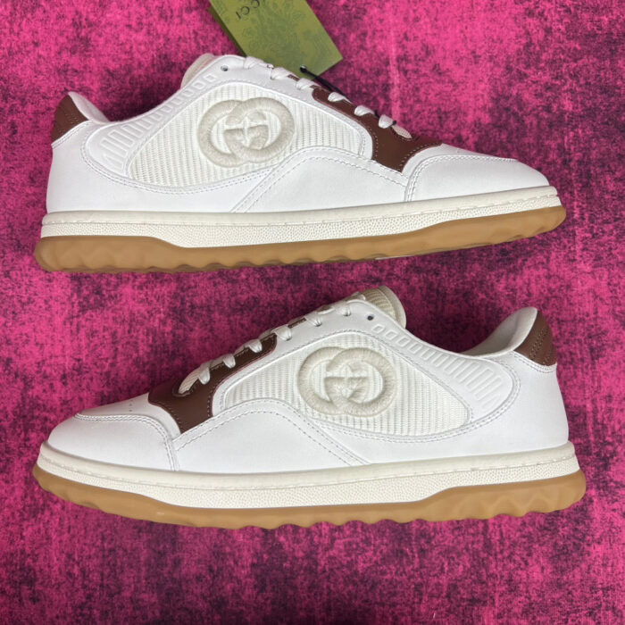 Scarpe Gucci sneakers in pelle e gomma, stile elegante e moderno su sfondo rosa vibrante.