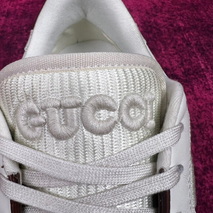 Sneaker bianca con logo euco e dettagli moderni su sfondo viola vibrante.