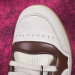 Sneaker elegante in pelle crema e marrone con dettagli di qualità e stile moderno.