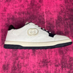 Sneaker bianca di lusso con logo doppio G e dettagli eleganti su sfondo rosa vivace.