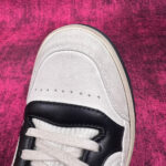 Sneaker bianca con dettagli neri su sfondo rosa vibrante, stile casual e moderno.