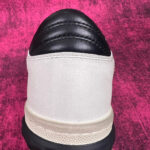 Sneaker elegante con tomaia in beige e dettagli in pelle nera, suola antiscivolo robusta.