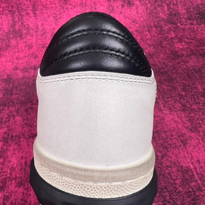 Sneaker elegante con tomaia in beige e dettagli in pelle nera, suola antiscivolo robusta.