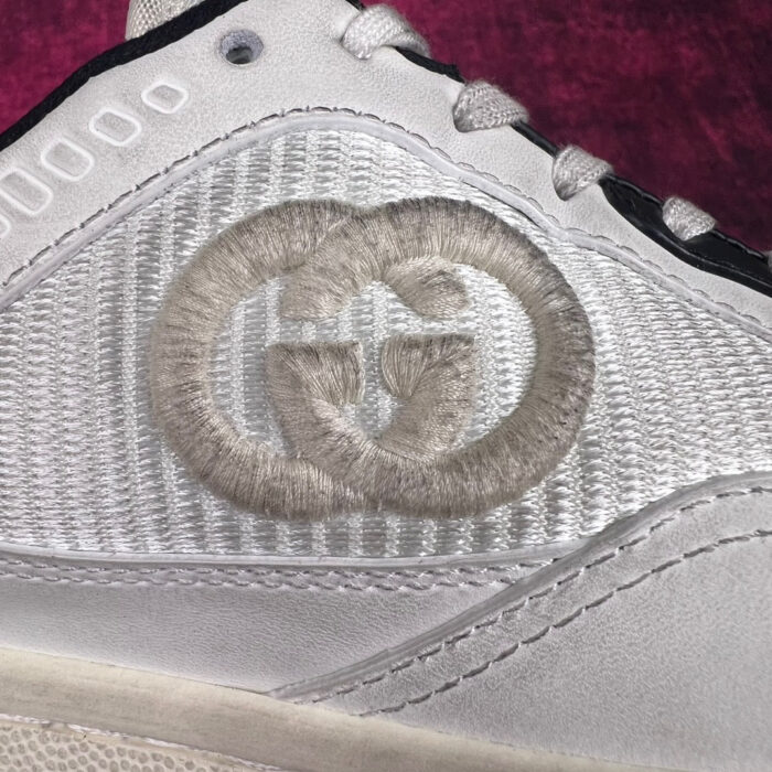 Sneaker di lusso in materiali metallizzati con logo embossato, dettagli eleganti e design contemporaneo.