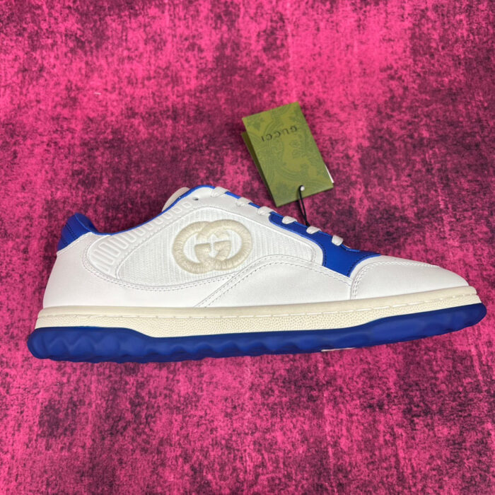 Sneaker di lusso bianca e blu con logo in rilievo su sfondo rosa vibrante.