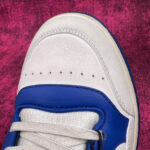 Sneaker bianca e blu, stilosa, moderna, con dettagli di alta qualità e design sportivo.