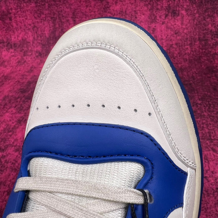 Sneaker bianca e blu, stilosa, moderna, con dettagli di alta qualità e design sportivo.