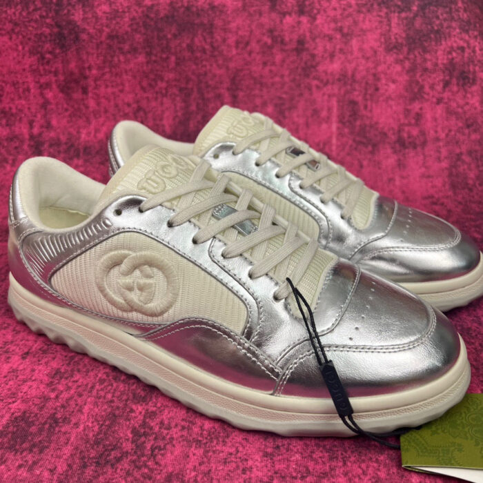Sneaker metallizzate di lusso con dettaglio elegante su sfondo rosa vibrante.