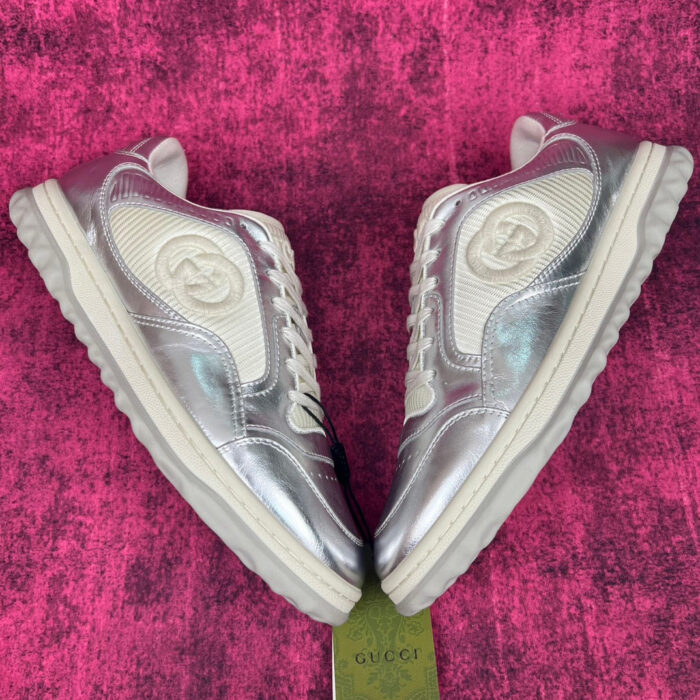 Sneakers iridescenti silver di lusso, moderne e chic su sfondo rosa vibrante.