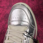 Scarpa sportiva silver con lacci crema su sfondo magenta, design moderno e ventilazione.