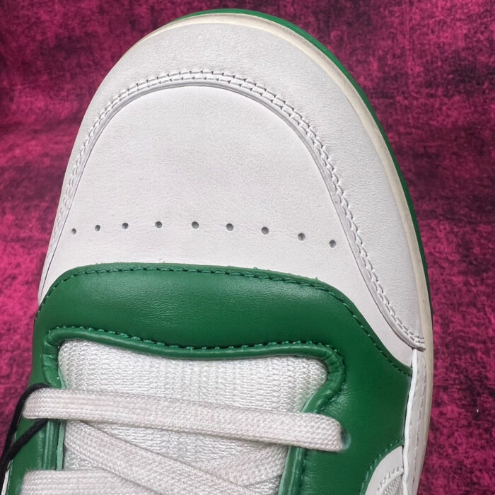 Sneaker bianca e verde in primo piano con dettagli in pelle e design sportivo.