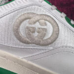 Sneaker bianca di lusso con logo ricamato e dettagli verdi, stile moderno ed elegante.