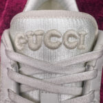 Sneaker Gucci bianca di lusso con logo morbido e design minimale, su sfondo elegante.