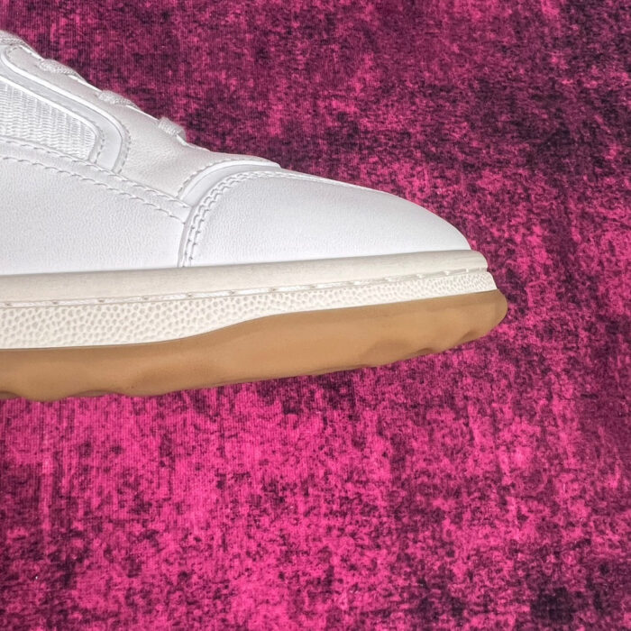 Sneaker bianco con suola in gomma su sfondo magenta, dettaglio moderno e stiloso.