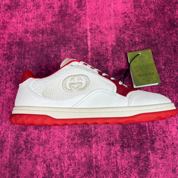 Sneaker di lusso bianca e rossa con logo discreto su sfondo rosa vibrante