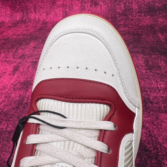 Sneaker bianca con dettagli rossi su sfondo rosa vibrante, stile moderno e design accattivante.