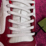 Scarpa da corsa bianca con dettagli rossi e etichetta verde, stile moderno e sportivo.