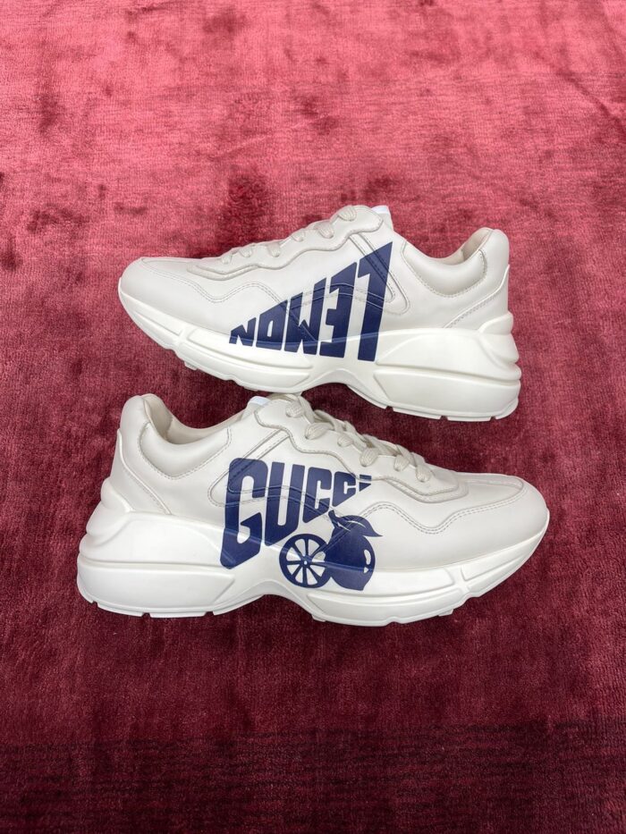 Sneakers Gucci moderne in bianco, con dettagli Navy su sfondo rosso cremisi elegante.