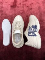Sneaker casual bianca con graphic blu, su sfondo rosso e interni comodi, stile trendy e sportivo.