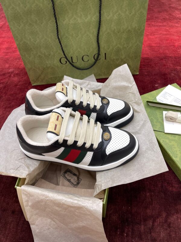 Scarpe Gucci di lusso con packaging elegante e dettaglio iconico verde e rossa.