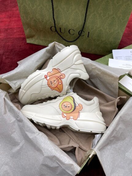 Sneakers Gucci con disegni giocosi in scatola di lusso con logo iconico verde.