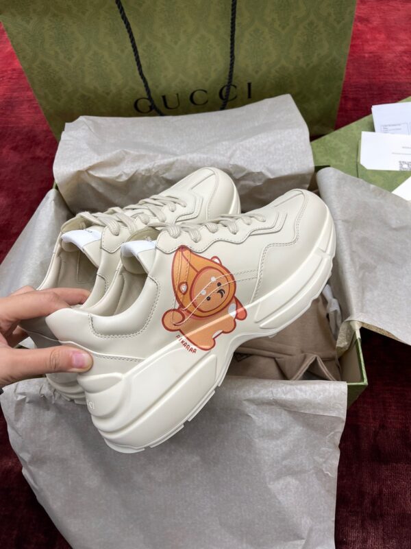 Sneakers Gucci beige con personaggio giocoso, packaging elegante e stile moderno di lusso