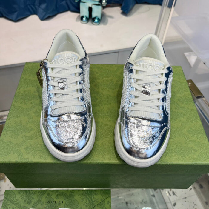 Sneakers metalliche argentate su scatola verde, stile moderno e trendy per look fashion.