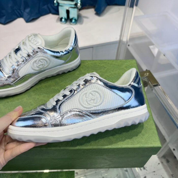 Sneakers di lusso bianche con dettagli metallici e logo prominente, perfette per uno stile moderno.