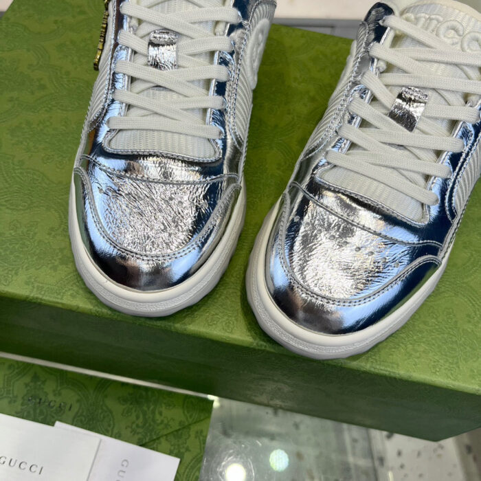 Sneakers bianche e argento di lusso su scatola verde sostenibile, stile moderno e innovativo.