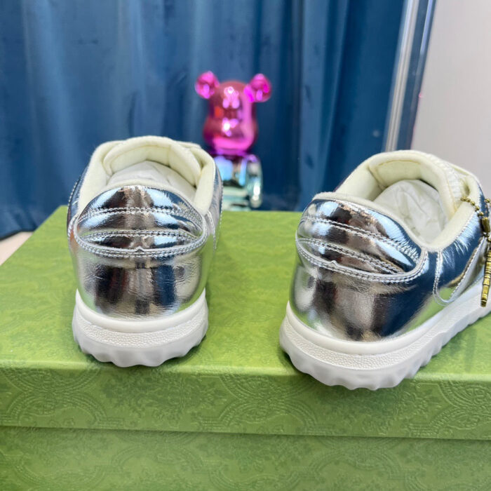 Sneakers silver metallizzate con dettagli eleganti e tocco giocoso, su scatola verde vivace.