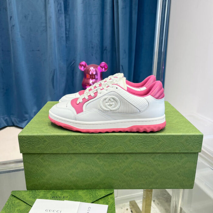 Sneaker bianche con dettagli rosa, box verde elegante e scena raffinata con pupazzo divertente.