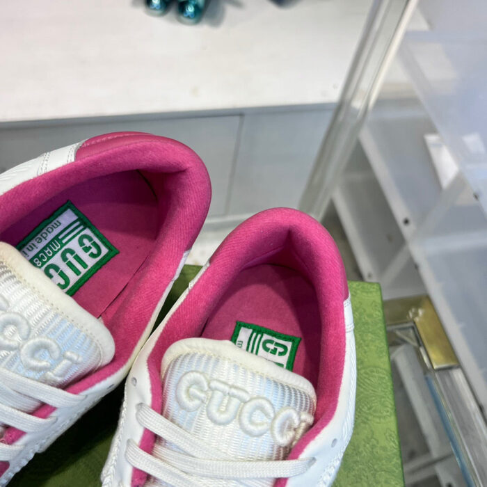 Sneakers Gucci bianche con fodera rosa e packaging verde, stile lussuoso e alla moda.
