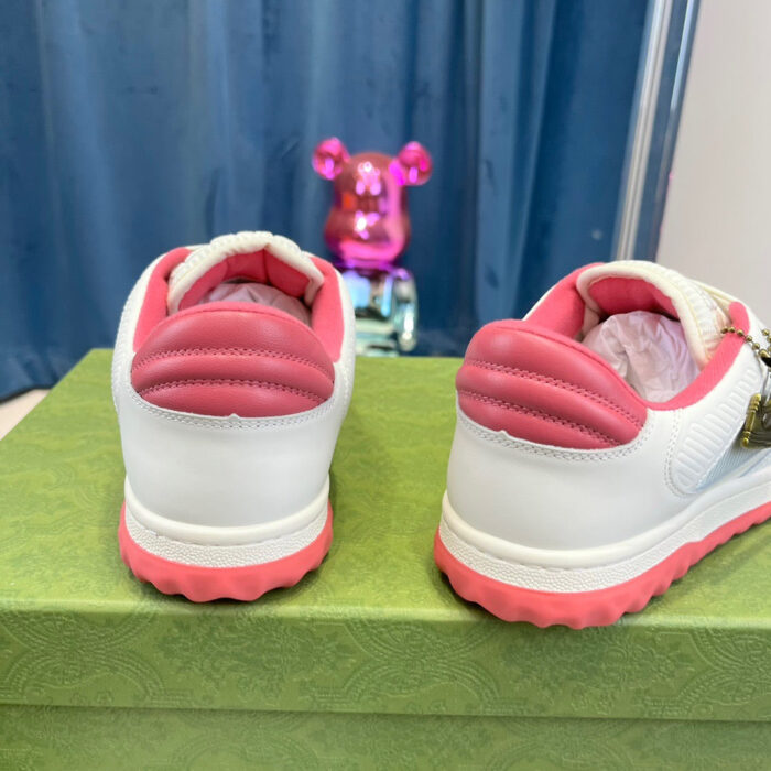 Sneakers bianche con dettagli rosa, su scatola verde, con figure giocosa sullo sfondo