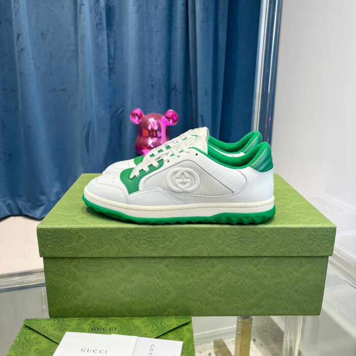 Sneakers bianche con dettagli verdi e figura giocattolo, stile sportivo e vivace.