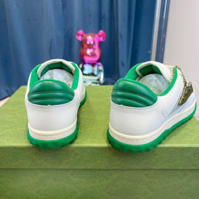 Sneakers sportive bianche con dettagli verdi e tocchi dorati, stile moderno e creativo.