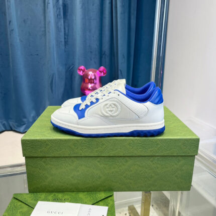 Scarpe sneakers bianche e blu su scatola verde, sfondo blu e 或oso orsetto rosa.