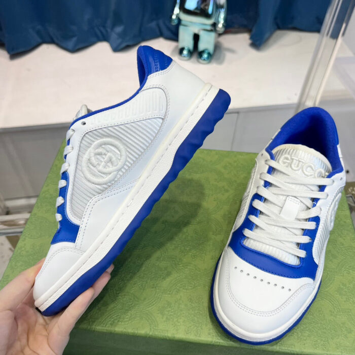Sneakers bianco e blu alla moda su sfondo verde con dettagli moderni e comfort garantito.