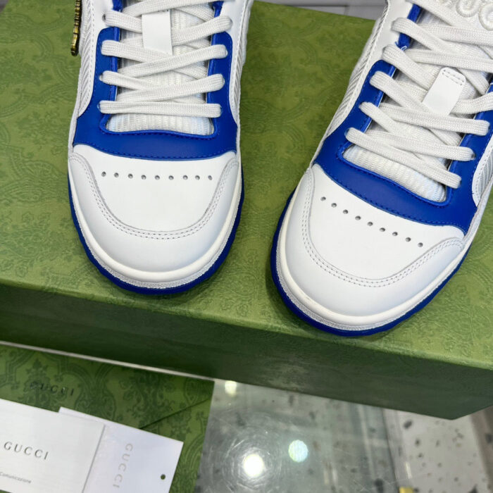 Sneakers Gucci bianche e blu su scatola verde di lusso, stile elegante e sportivo.