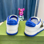 Sneakers bianche con dettagli blu, figura giocosa rosa e sfondo blu, stile streetwear giovane.