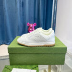 Sneaker bianca elegante su scatola verde con decorazioni colorate e dettagli di lusso.