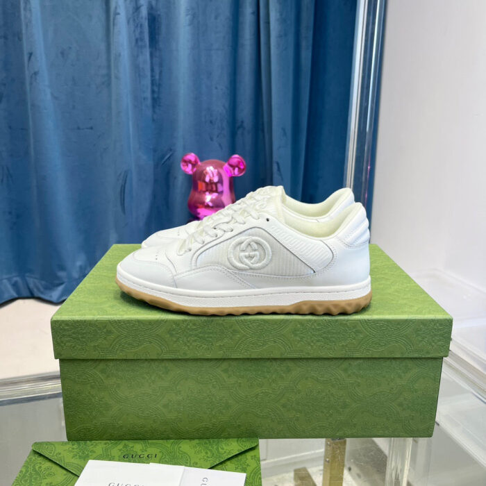 Sneaker bianca elegante su scatola verde con decorazioni colorate e dettagli di lusso.