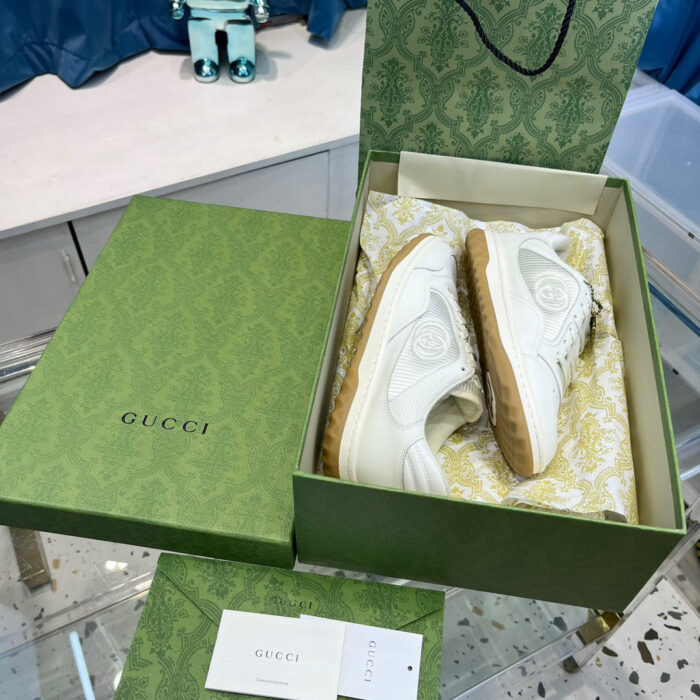 Scatola Gucci con sneakers bianche di lusso, dettaglio elegante e presentazione di alta qualità.